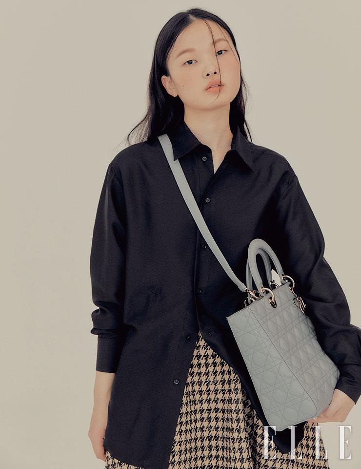 간결한 블랙 실크 셔츠와 그레이 컬러 레이디 디올 백, 하운즈투스 체크 패턴의 스커트는 모두 Dior.
