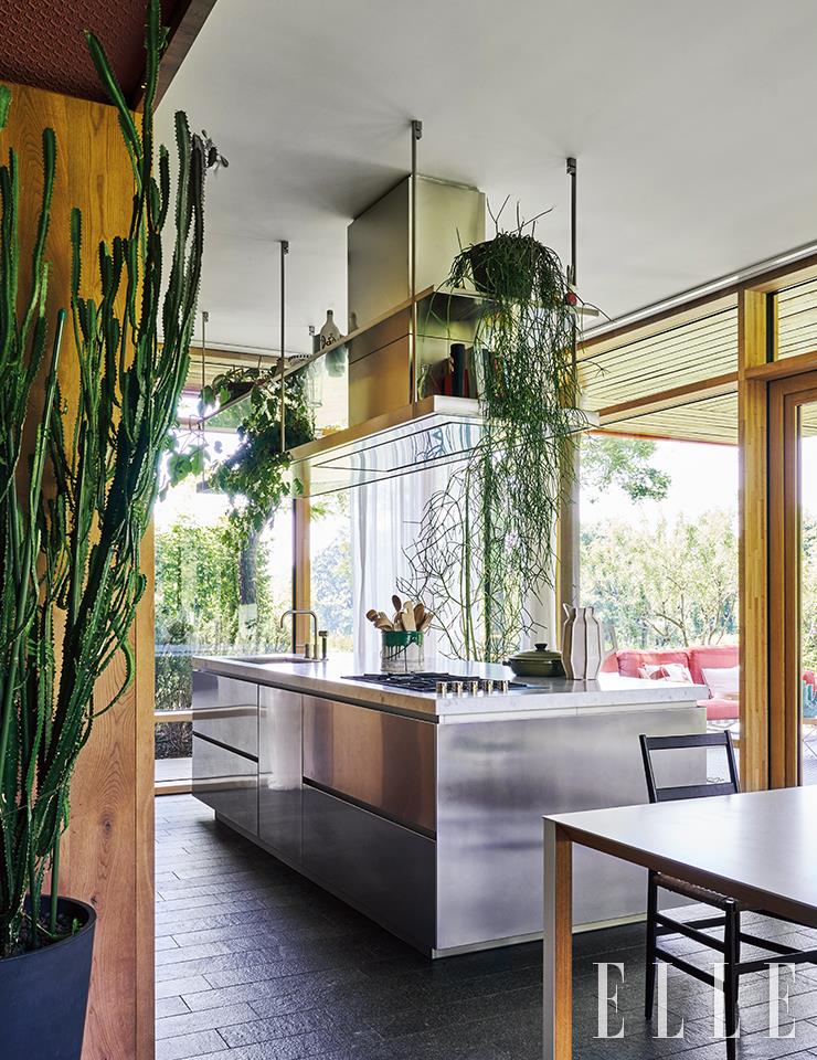 강철 소재의 폴리폼(Poliform)의 주방 가구가 목재와 식물과 어우러진 키친 룸.