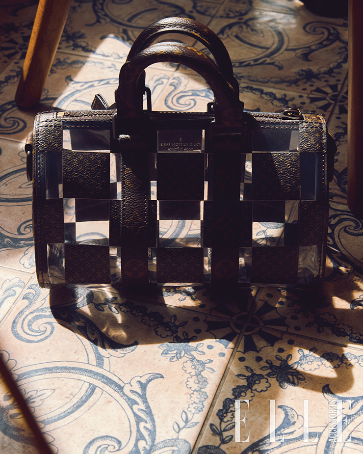 모노그램 캔버스와 투명한 PVC 소재의 체스 패턴 디테일 숄더백은 Louis Vuitton.