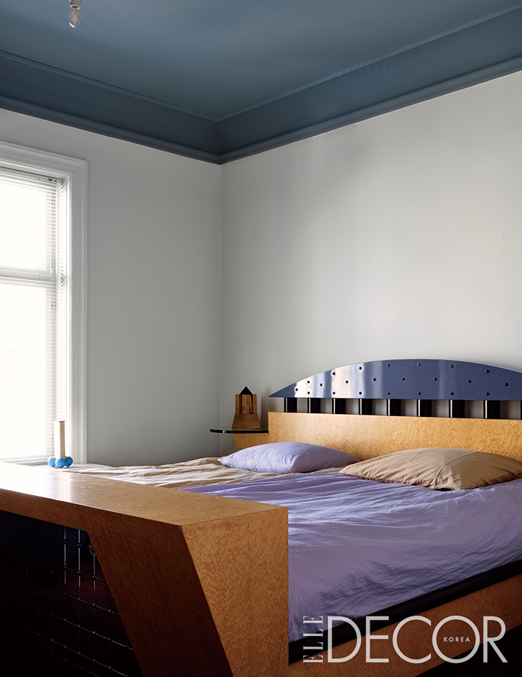 멤피스 브랜드인 마이클 그레이브스의 ‘스탠호프(Stanhope)’ 침대는 압도적인 아우라로 이 공간을 지배한다. 침구는 테클라(Tekla)의 제품들로 꾸몄다. 창가에는 마사노리 우메다(Masanori Umeda)의 ‘오리노코(Orinoco)’ 화병이 놓여 있다.