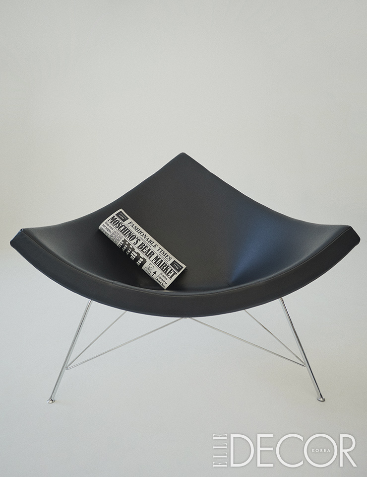 모노크롬 컬러의 넬슨 코코넛 라운지 체어는 Herman Miller by Innovad. 신문 모티프의 클러치백은 Moschino.